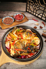 Fish Head Casserole with Soy Sauce and Spices in Traditional Black Pot on Wooden Table