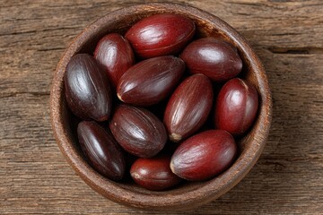 Dark-red seeds in a wooden bowl on a rustic table