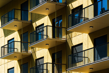 Residential building façade with yellow balconies and railing symmetry captured from dramatic...