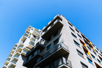 Modern residential building with stacked balconies and clean geometric design rising against a...