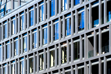 Minimalist office façade with sharp white panels and narrow vertical windows forming rhythm and...