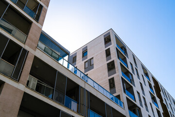 Modern residential complex with diverse apartment buildings, balconies, and urban design under bright blue sky.