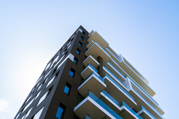 Modern residential building with stacked balconies and clean geometric design rising against a...