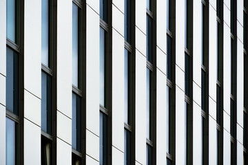 Minimalist office façade with sharp white panels and narrow vertical windows forming rhythm and...