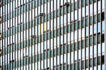Old office building façade with repetitive window pattern, aged green panels, and visible air conditioning units.