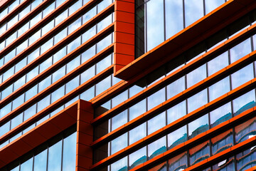 Modern office building with geometric glass façade featuring open windows, strong symmetry, and...