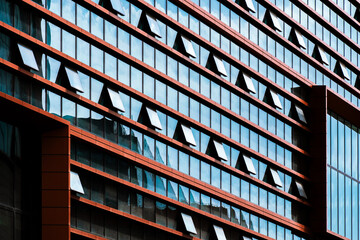 Modern office building with geometric glass façade featuring open windows, strong symmetry, and...