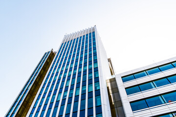 Modern high-rise office tower with sleek vertical lines and glass façade rising against a clear...