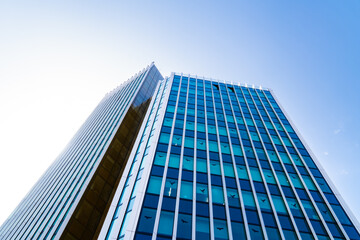 Modern high-rise office tower with sleek vertical lines and glass façade rising against a clear...