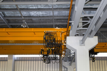 Overhead crane at side view in industrial building. Machine or lifting equipment with hoist, hook and wire rope for move operate heavy load in manufacturing production and freight shipping transport.