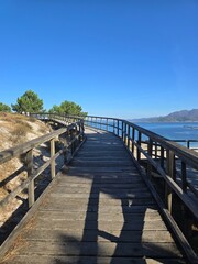 A wooden bridge overlooking the beach, providing a peaceful and serene atmosphere for walking along the sea. 