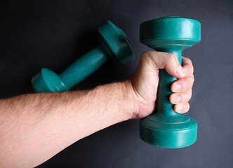 Pesas y mancuernas pequeñas verdes de un kilo de gimnasio para deporte y ejercicio en mano de...