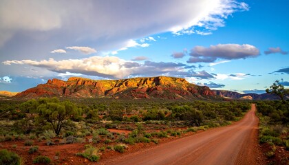 A dirt road winds through a colorful desert landscape at sunset