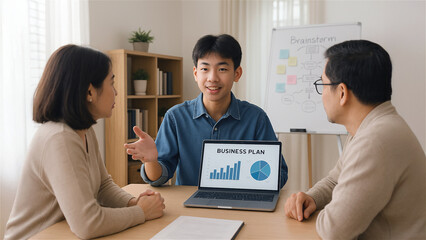 A young Asian male presenting a business plan on a laptop to his attentively listening parents. The teenager is confident, gesturing towards the laptop screen with graphs and charts.