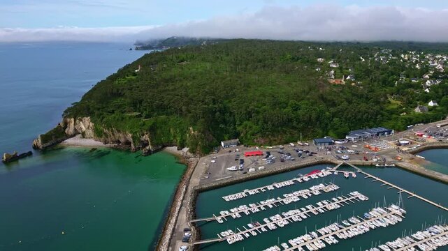 Aerial of Morgat marina and boats docked in calm bay, Crozon Peninsula, Brittany, establishing pullback overview