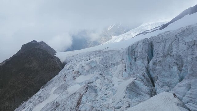 Aerial revealing massive Steingletscher glacier with deep blue crevasses, surrounded by rocky mountains under cloudy sky, Susten Pass, Swiss Alps, Switzerland