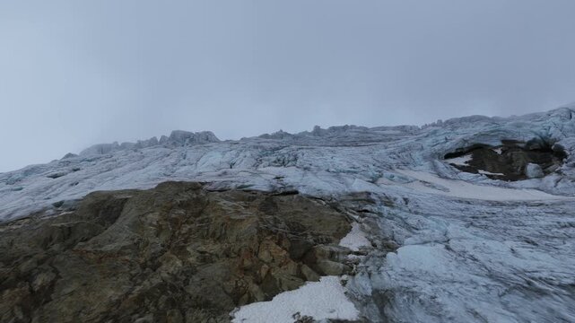 Close aerial flying over surface of Steingletscher glacier, showing textures of ice and snow on a cloudy day, Susten Pass, Swiss Alps, Switzerland