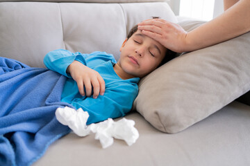 Flu, fever and mother with sick boy for health, virus or infection symptoms in bedroom. Family, childcare and hand of parent with child at home in couch to check temperature for cold, illness and flu