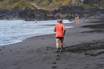 Man jogging on black sand beach