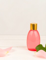 Pink bottle of rose-scented liquid with rose petals and leaves