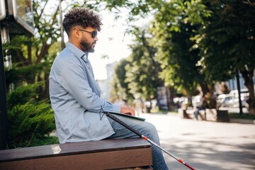 Special Braille technique for reading. Blind man with white cane and sunglasses is in the city