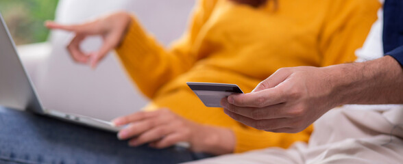 Closeup happy asian couple using laptop and credit card for online shopping together in living room at home, man and woman relax with enjoy a digital lifestyle, convenient payment.
