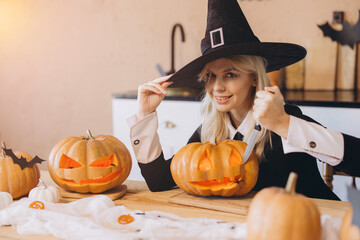 Young woman carving Halloween pumpkins wearing witch costume