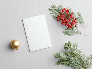 Fototapeta premium Elegant christmas holiday flat lay with blank invitation card mockup for festive message. Sustainable decoration with green branch red berry and gold ornament create cheerful mood
