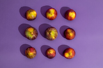 Pattern made of fresh figs on purple background. Flat lay, top view. Food Photo. Creative scheme of the whole and sliced figs  inscribed in a rectangle. Copy space