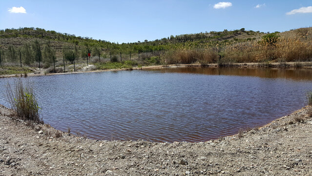 A landfill leachate evaporation pond containing contaminated, reddish-brown water, situated in a remote, arid landscape, representing a method for waste treatment.