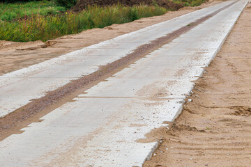 The road is lined with concrete slabs. Access road to the construction site.