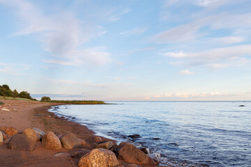 Large boulders on the seashore in the rays of the setting sun. Seascape.