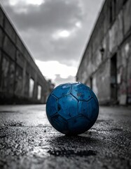 Blue soccer ball lying on wet asphalt in deserted urban area