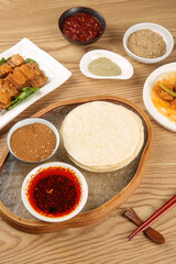 Asian barbecue meal with pancakes, sauces and spices on wooden table - traditional cuisine setup