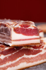 Traditional Smoked Bacon Slabs with Rich Marbling and Deep Red Color on Rustic Wood Surface