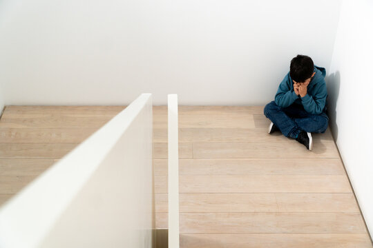 Sad preteen in corner of room experiencing bullying