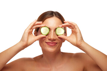 A woman enjoys a refreshing skin care routine with cucumber slices placed over her eyes,...