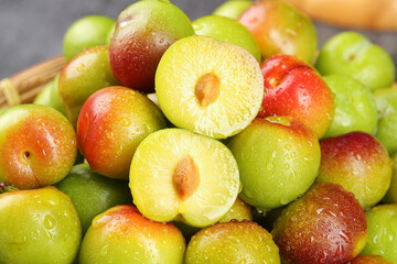 Fresh Ripe Plums Cut in Half Showing Juicy Yellow Flesh and Stone Pits with Water Droplets