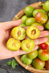 Fresh Szechuan Plums Cut in Half Showing Deep Yellow Flesh and Stone Pit in Hand