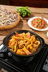 Stir-fried eggplant and bacon in cast iron skillet with noodles on wooden table
