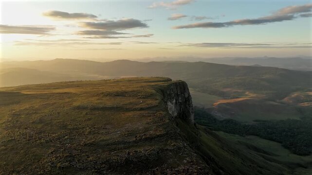 Aerial view of the dramatic Chiricayen Tepui, where the sun casts a golden glow over the cliff and grassy plateau, Santa Elena de Uairen, Venezuela.
