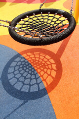 A black spider web swing in colorful playground. Resemble bird nest in shape and able to carry multiple people. One of popular play installation at children's playground.