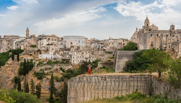 Woman in historic architecture of Gravina, Puglia under a vast sky