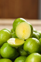 Fresh Green Plums with Yellow Flesh Cut in Half on Wooden Background