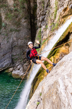 Woman rappelling down a waterfall in adventure gear