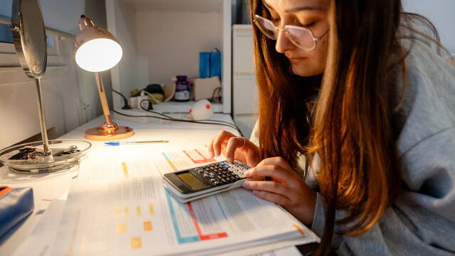 Girl studying with calculator at home desk