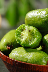Fresh Mini Kiwi Fruits in Wooden Bowl - One Cut Half Showing Green Flesh and Seeds