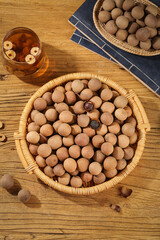 Dried Longan Fruit in Traditional Baskets with Herbal Tea on Rustic Wood Table