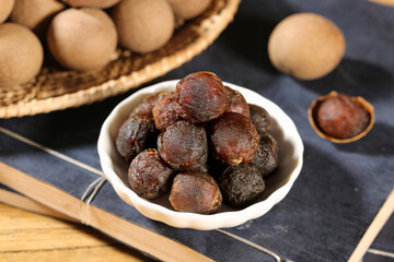 Dried Longan Fruit Seeds Stacked in Bowl with Fresh Kernelless Varieties on Slate Board