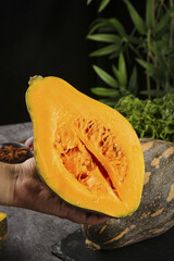 Fresh Orange Pumpkin Half with Seeds Held in Hand for Cooking and Baking Ingredients